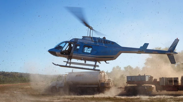 Helicopter landing after day of field work, kicking up dust and debris